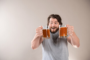 Portrait of a happy young bearded man holding two beer mugs isolated over light gray background