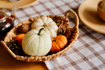 basket with small decorative white and orange pumpkins and cones.