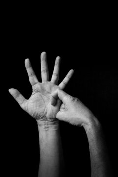 B+W image of hand demonstrating BSL sign language letter R isolated against black background