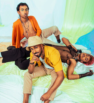 Malaysian Indian men laughing and posing together against a cloth backdrop in a studio setting, wearing fashionable clothing