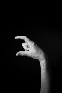 B+W image of hand demonstrating BSL sign language letter C isolated against black background