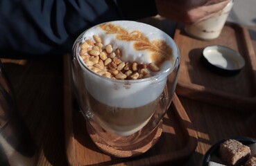 Coffee with whipped cream and pine nuts on a wooden stand.