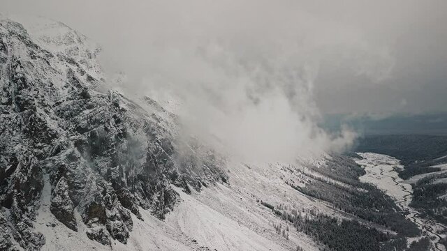 Storm, snowfall in the huge glacier of Mount Belukha, the valley of the Aktru River, the Altai Mountains. Cloudy weather, stone in the snow, storm, wildlife, winter forest, frozen mountain river in