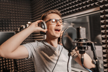 The vocalist sings in the studio in a microphone. Man in headphones writes a podcast, an audiobook. Artist, recording an album, working with the label. Announcer records a speech at a radio station
