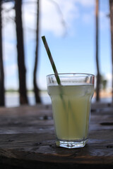 Refreshing lemonide next to the lake during sunny day with trees in the background