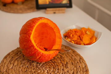 scooping a pulp and seeds out of pumpkin in the kitchen to make a jack-o-lantern