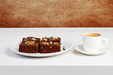 Homemade brownie and cup of coffee espresso on white wooden table. Copyspace.