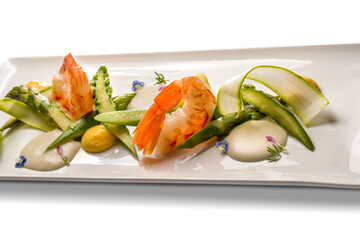Shrimps with asparagus and zucchini, gourmet recipe in white dish isolated on white, copy space
