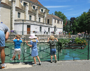 Obraz na płótnie Canvas Children looking into the river and planters, Annecy, Haute-Savoie, France