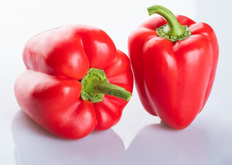Two Beautiful young red bell peppers with a green branch isolated on a white background
