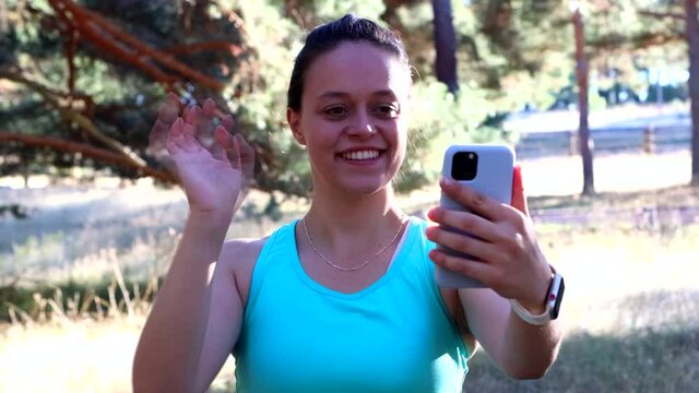 4K video of young athlete girl making a video call with her cell phone after having trained. girl waving at camera.
