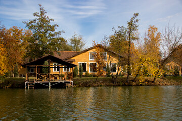 Obraz premium House on the banks of the river in the trees