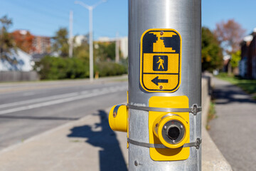 Yellow pedestrian push button sign on traffic signal pole at crosswalk in Ottawa street, Canada