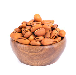 Pine nuts in wooden bowl, isolated on white background. Heap of roasted pine nuts in shells.