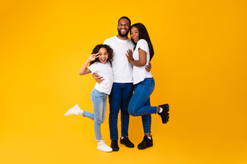 African American man hugging his wife and playful daughter