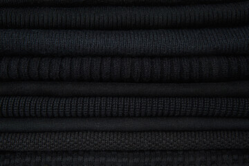 A stack of black things, clothes of different textures. Fabric texture, background. - Powered by Adobe