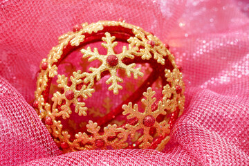 Christmas ball with golden snowflakes lies in a soft pink fabric. Christmas composition - 465809939