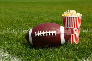American football ball with popcorn on green field grass outdoors