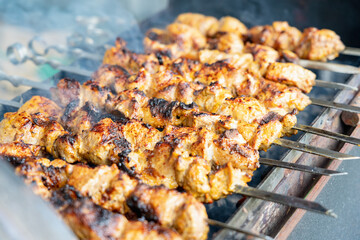 Pork shashlik on metal skewers. Smoke from burning fat. Selective focus