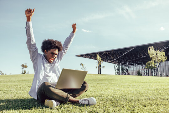 Profile Side Photo Of Dark Skin Happy Victorious Man Sit Grass Look Computer Win Outside In Outdoors Park