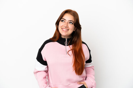 Young redhead woman isolated on white background thinking an idea while looking up