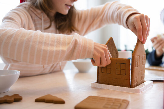 Girl Making Gingerbread House At Table