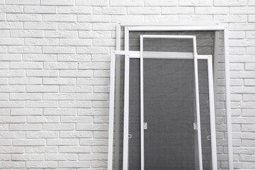 Set of window screens near white brick wall. Space for text