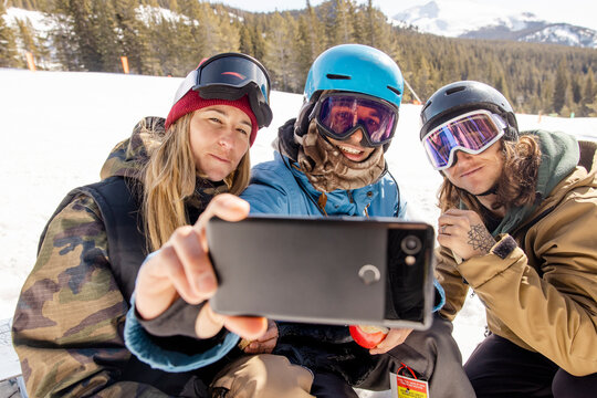 Happy snowboarding friends taking selfie on slope