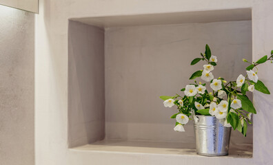 Fototapeta na wymiar White flowers plant in a metal pot on a wall shelf, empty space, room interior template