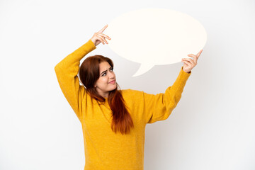 Young redhead woman isolated on white background holding an empty speech bubble and with sad expression