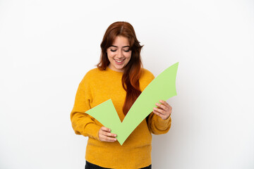 Young redhead woman isolated on white background holding a check icon and looking it