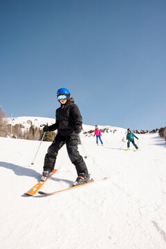 Boy Downhill Skiing On Sunny Snowy Mountain Slope