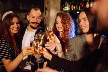 Group of friends partying in a nightclub and toasting drinks with champagne. Happy people enjoying winter holiday. Party, celebration, drink, birthday concept.