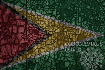 flag of guyana on a old metal rusty cracked wall with text coronavirus, covid, and virus picture.