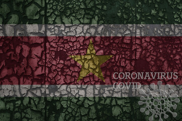 flag of suriname on a old metal rusty cracked wall with text coronavirus, covid, and virus picture.