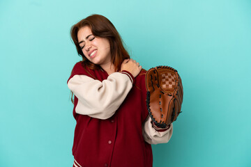 Young redhead woman playing baseball isolated on blue background suffering from pain in shoulder...