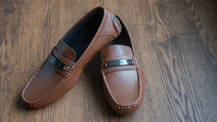 BROWN MOCCASIN SHOES, ON WOODEN FLOOR WITH NATURAL LIGHTING AND SPACE FOR TEXT