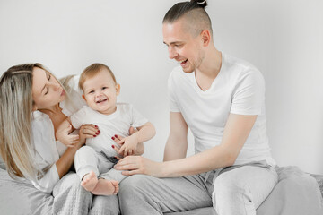 Fototapeta na wymiar Happy family. Smiling mother and father playing with their baby son. White background.