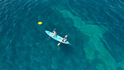 Aerial drone photo of fit couple practising on a colourful canoe in turquoise open ocean bay with crystal clear sea