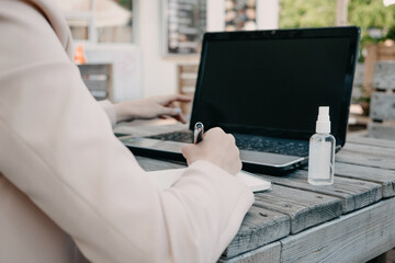 Working, Outdoors, Remote work. Redhead Business woman drinking coffee and working on the laptop outdoors. Young Businesswoman working on laptop outside.