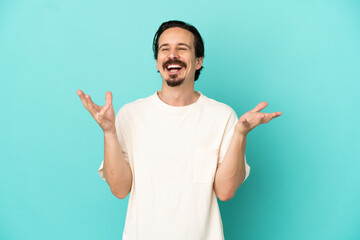 Young caucasian man isolated on blue background smiling a lot