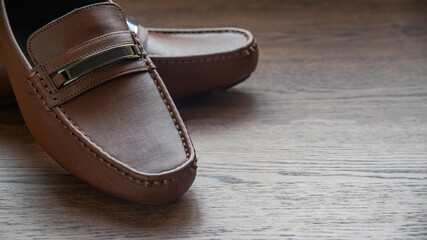 BROWN MOCCASIN SHOES, ON WOODEN FLOOR WITH NATURAL LIGHTING AND SPACE FOR TEXT