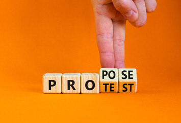 Propose instead protest symbol. Businessman turns wooden cubes, changes the word 'protest' to 'propose'. Beautiful orange table, orange background. Business, protest or propose concept. Copy space.