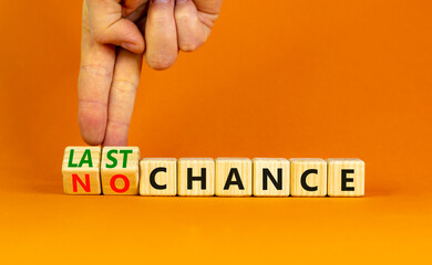 No or last chance symbol. Businessman turns wooden cubes and changes words 'no chance' to 'last chance'. Beautiful orange background, copy space. Business and no or last chance concept.