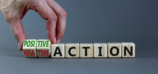 Positive or negative action symbol. Businessman turns cubes and changes words negative action to positive action. Beautiful grey background, copy space. Business positive or negative action concept.
