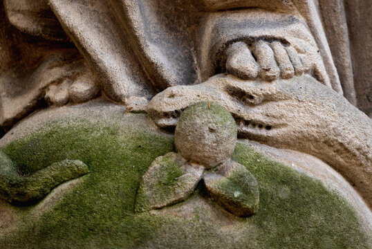 Religious symbol of Christianity: Close up Virgin Mary crushing with her foot the serpent as a symbol of the victory of good over evil. Fragment of an ancient statue. Horizontal image.