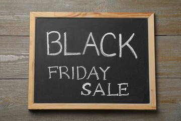 Chalkboard with words Black Friday Sale on wooden table, top view