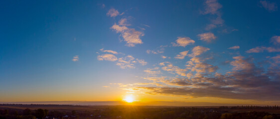 Fototapeta na wymiar Panorama of sunrise. Blue sky with orange clouds.
