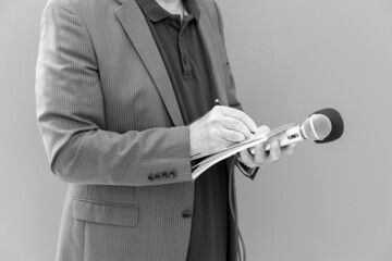 Journalist or news reporter holding microphone and taking notes at press conference or media event
