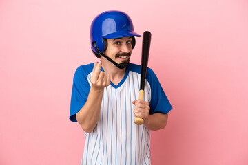 Young caucasian man playing baseball isolated on pink background making money gesture